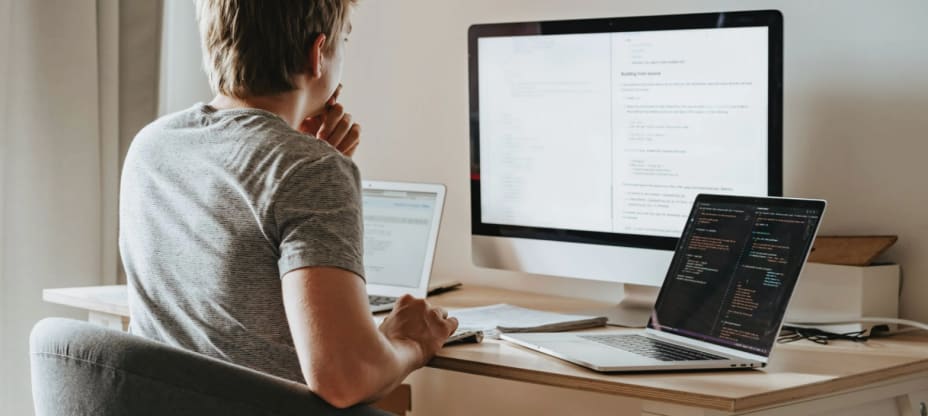 young man sitting behind the multiple screens working on Knowledge Management System