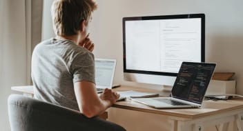 young man sitting behind the multiple screens working on Knowledge Management System