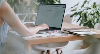 a woman sitting by a desk with a computer on it