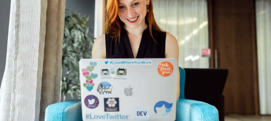 a red-haired woman sitting with a laptop on her lap