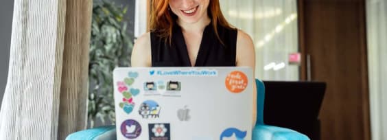 a red-haired woman sitting with a laptop on her lap