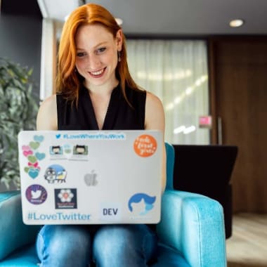 a red-haired woman sitting with a laptop on her lap