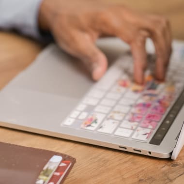 A hand holding a credit card and typing on laptop