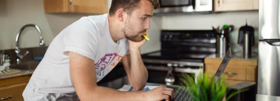 a man standing in front of a computer in kitchen