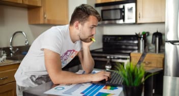 a man standing in front of a computer in kitchen