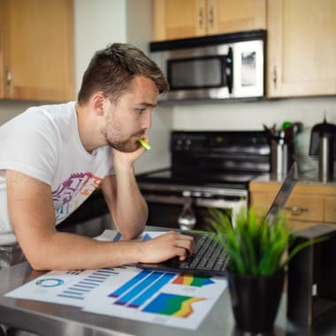 a man standing in front of a computer in kitchen