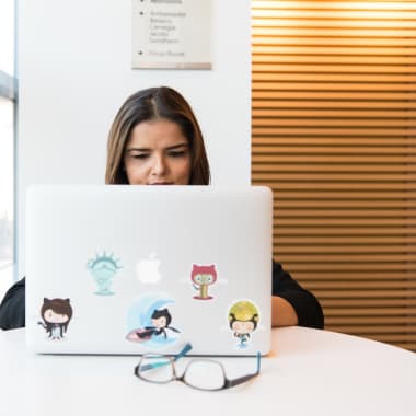 a woman sitting in front of a macbook