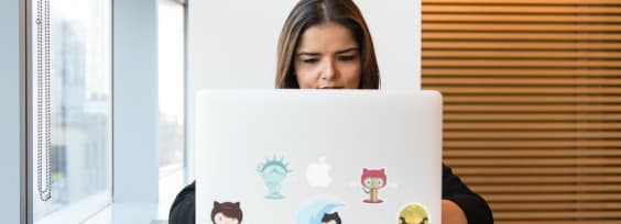 a woman sitting in front of a macbook