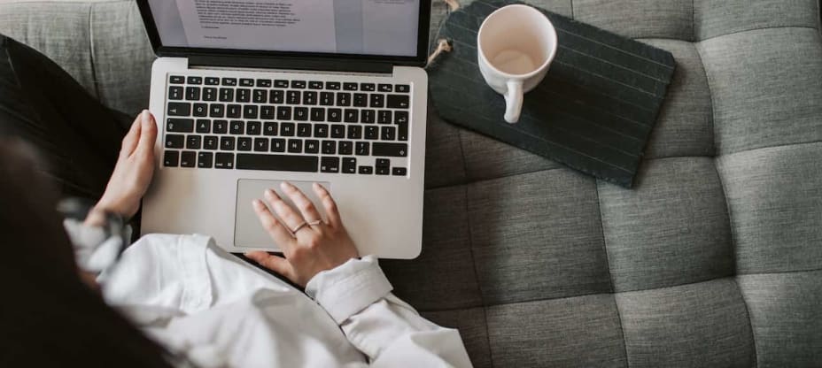 A woman sitting in front of a laptop at a couch