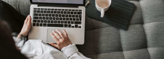 A woman sitting in front of a laptop at a couch