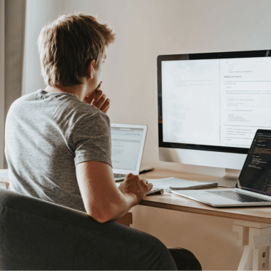 young man sitting behind the multiple screens working on Knowledge Management System